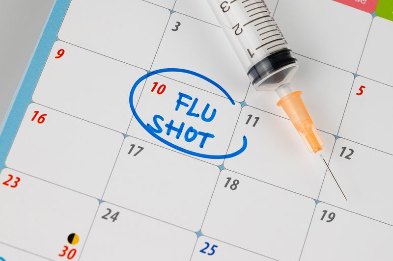 calendar with "Flu Shot" written in the square for the 10th of the month, in blue ink and circled, next to a syringe