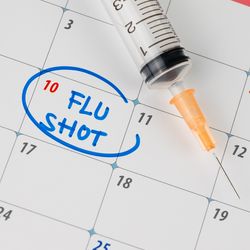 calendar with "Flu Shot" written in the square for the 10th of the month, in blue ink and circled, next to a syringe