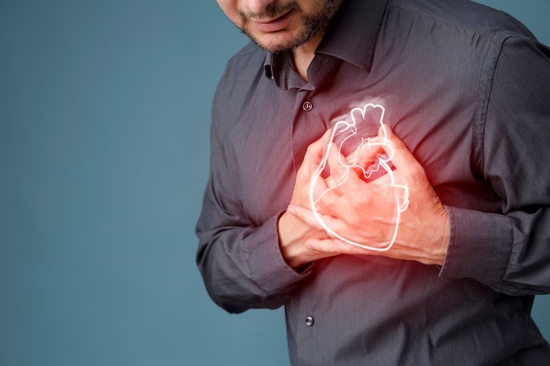 Bearded person clutching their chest with both hands, a glowing illustration of an anatomical heart superimposed over their hands