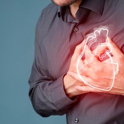 Bearded person clutching their chest with both hands, a glowing illustration of an anatomical heart superimposed over their hands