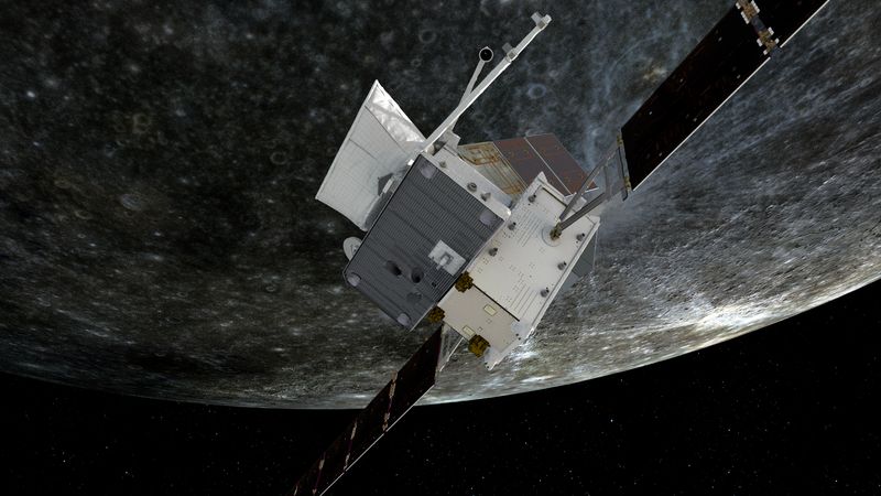 The spacecraft, quite boxy with solar panel spread out is in the foregroun. behind an image of a heaviley cratered grey world