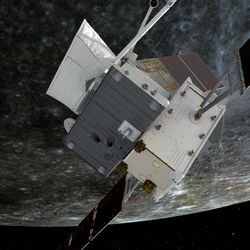 The spacecraft, quite boxy with solar panel spread out is in the foregroun. behind an image of a heaviley cratered grey world