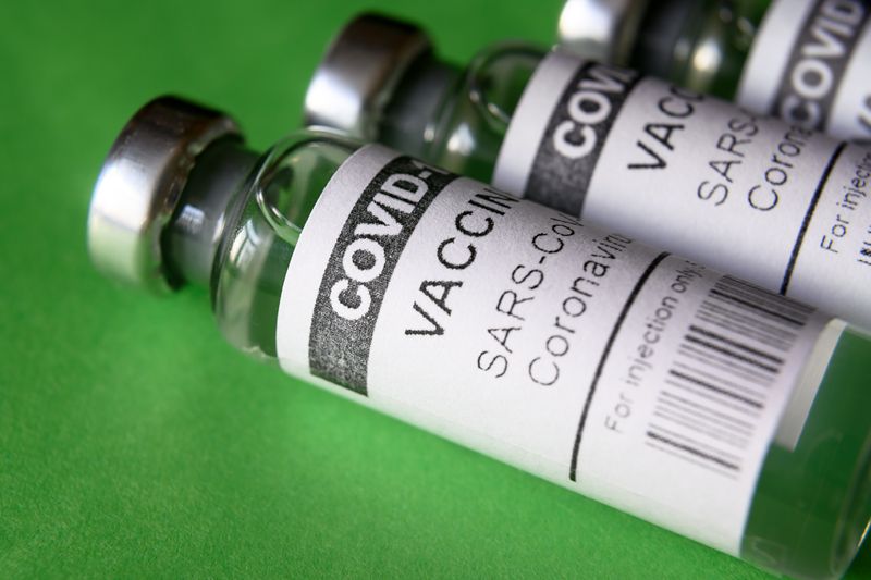 vials of COVID-19 vaccine against a green background