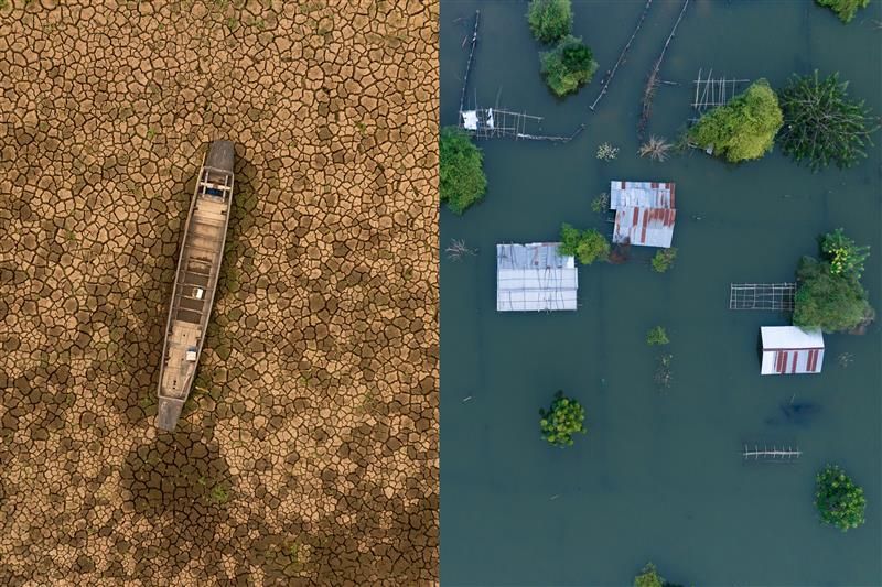 Two photos side-by-side. The photo on the left shows an aerial photo of a dried up river with a boat stranded in the middle. The ground is cracked and brown. The photo to the right shows another aerial view but this one is of a flooded settlement. The metallic roofs of buildings appear above the water's surface along with those of the surrounding trees. 