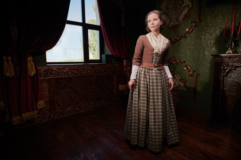 A lovely aristocratic girl in an 18th century Scottish dress stands in a room with classic vintage interior. The heroine of the novel. 18th century style. 