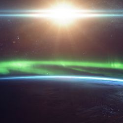 Artist impression of the northern lights from space over the limb of our planet with the Sun behind