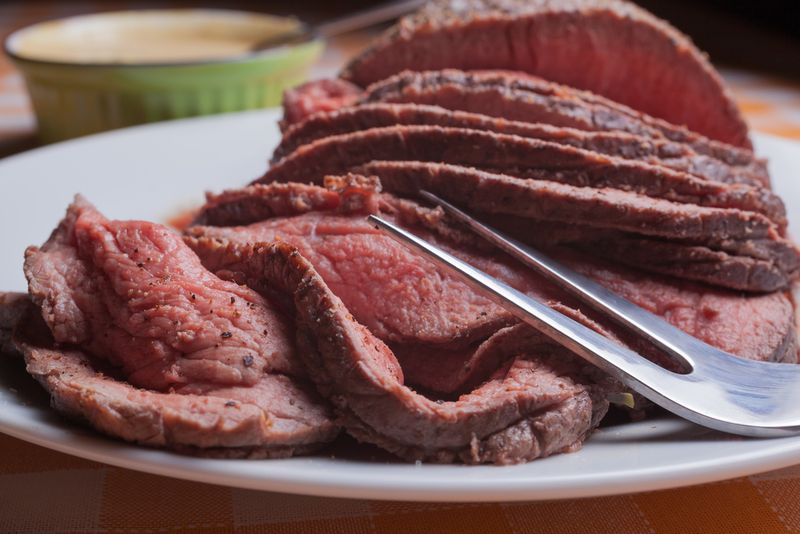 Roast beef on orange tartan tablecloth.