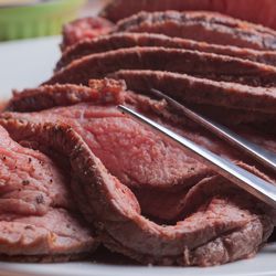 Roast beef on orange tartan tablecloth.