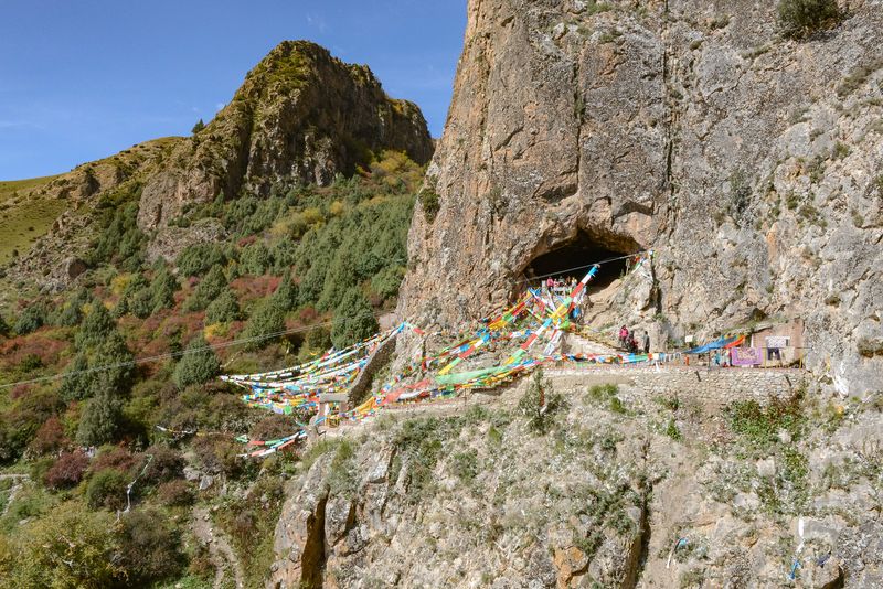  Photograph of the entrance of Baishiya Karst Cave, adorned in colorful fabric on a sunny day