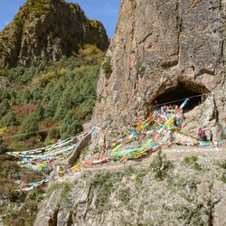  Photograph of the entrance of Baishiya Karst Cave, adorned in colorful fabric on a sunny day