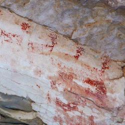 Looking up from Bright Angel Trail, a row of red pictograph deer are visible under an overhang.