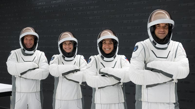 The four members of the crew wearing their spacesuits posing with crossed arms and smiling