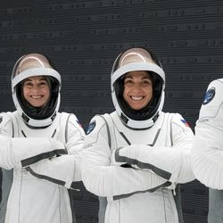 The four members of the crew wearing their spacesuits posing with crossed arms and smiling