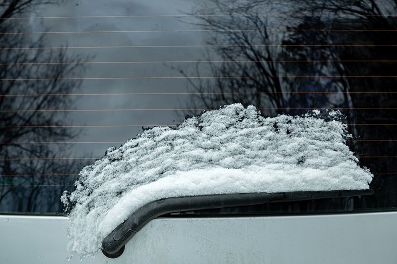 windshield wiper of the rear window of a car covered with a layer of snow thawed from the glass as a result of heating with heating strips, close-up.