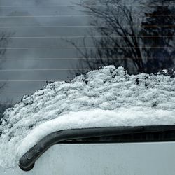 windshield wiper of the rear window of a car covered with a layer of snow thawed from the glass as a result of heating with heating strips, close-up.