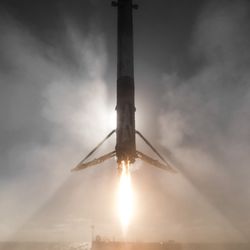 a rocket booster firing a retrorocket as it is about to land on a barge