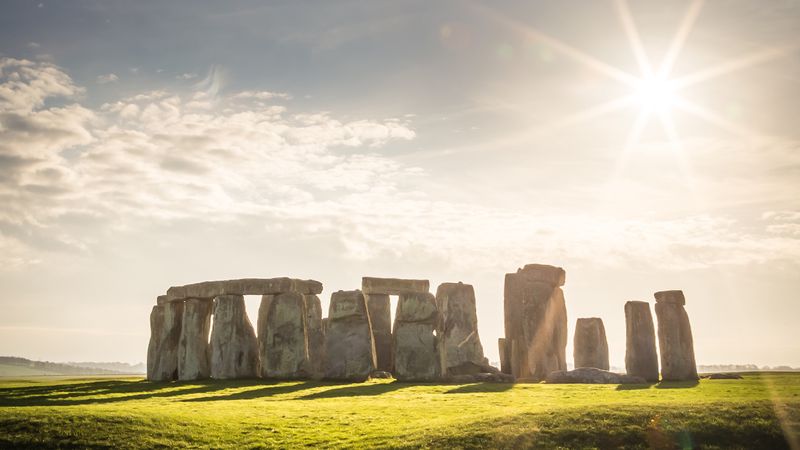 An image of Stonehenge in full sunshine. The circle of stones os clearly visible