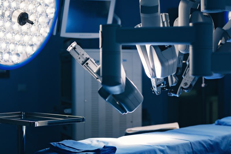 surgical robot above bed in operating room with bright light