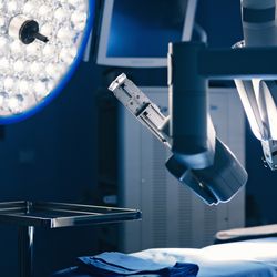 surgical robot above bed in operating room with bright light