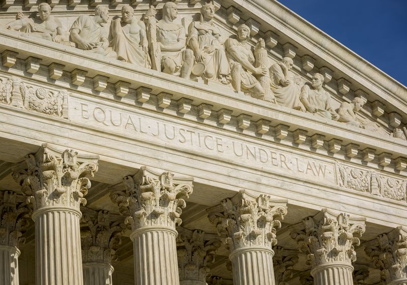 A photos of the front face of the US Supreme Court showing historical figures carved into the arch and the phrase "Equal Justice Under Law" under it. 