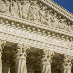 A photos of the front face of the US Supreme Court showing historical figures carved into the arch and the phrase "Equal Justice Under Law" under it. 