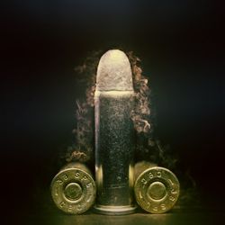 Three bullets on a black background, set out to look like a penis and testicles