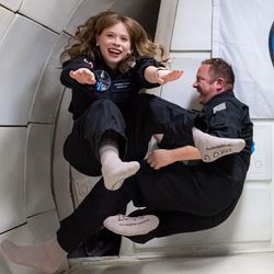 crew of Inspiration4 training in microgravity; 4 people in blue overalls floating around a white chamber