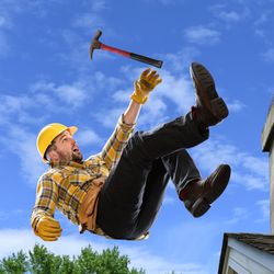 Worker wearing a hard hat falling off a roof