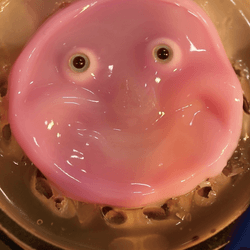 On the left, a 3D robot face covered with human skin tissue; on the right a pink, 2D face with large eyes