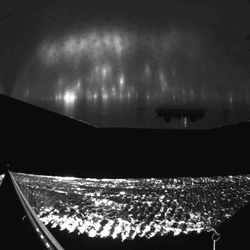  The Advanced Composite Solar Sail System has four black-and-white wide-angle cameras, centrally located aboard the spacecraft. Near the bottom of the photo, the view from one camera shows the reflective sail quadrants supported by composite booms. At the top of the photo is the back surface of one of the spacecraft’s solar panels. The five sets of markings on the booms close to the spacecraft are reference markers to indicate full extension of the sail. The booms are mounted at right angles, and the solar panel is rectangular, but appear distorted because of the wide-angle camera field of view.