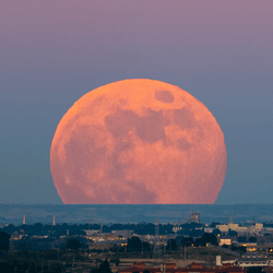 The moon looking particularly large (and red) against the backdrop of a Spanish city in June 2020. 