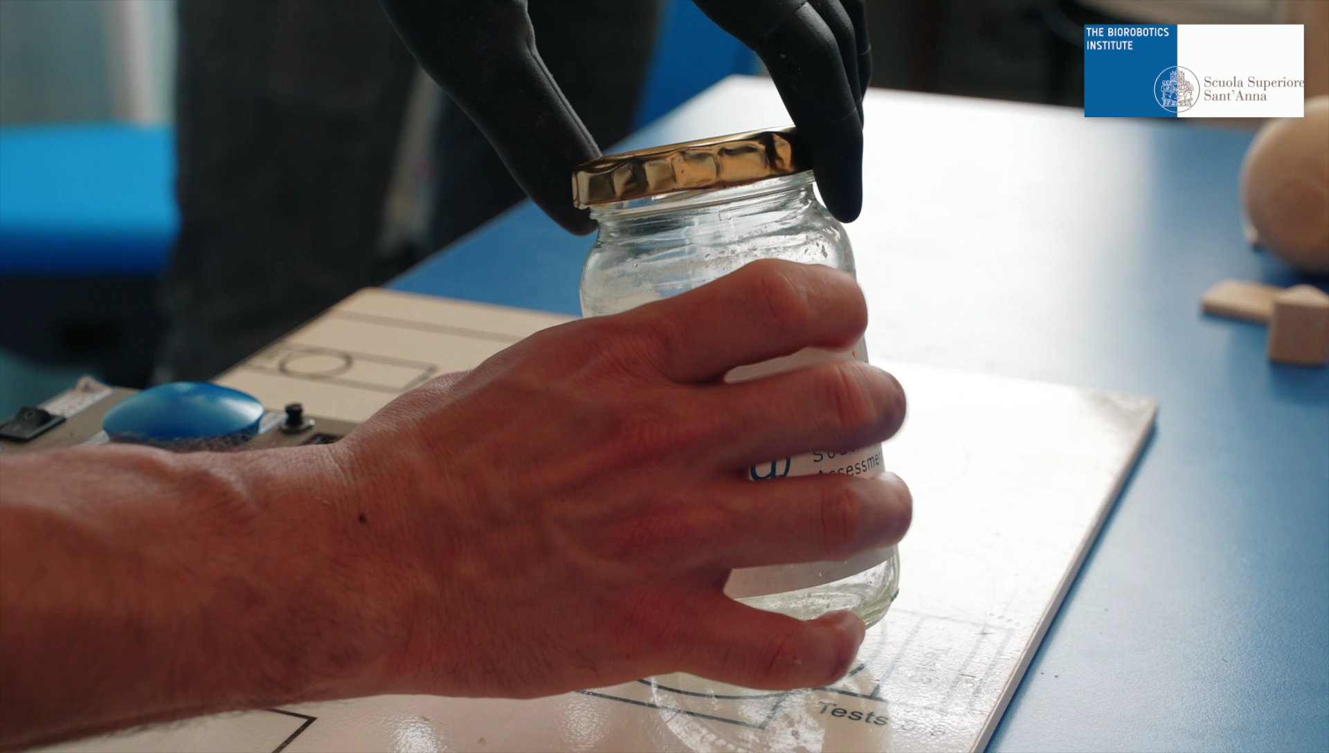 close up of human hand and prosthetic hand opening an empty jar