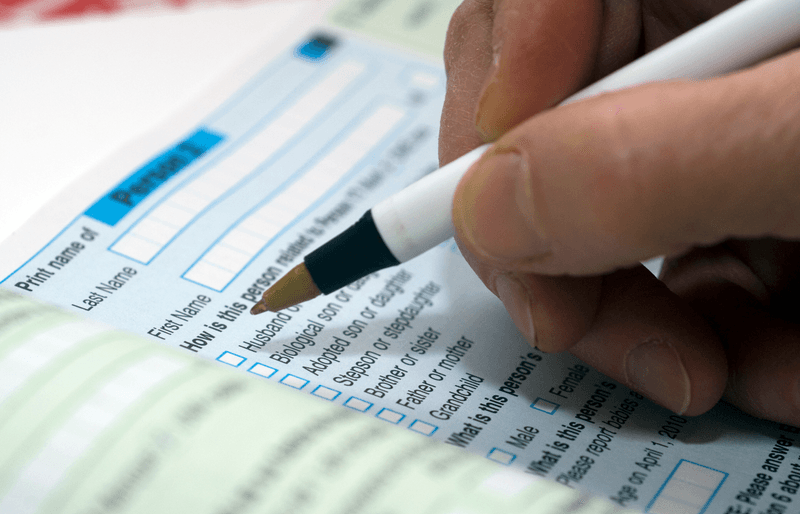 A hand holding a pen fills out the US Census in 2010.