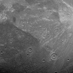 A partial view of ganymede. a few small craters are visible as well as many furrows, the concentric stripes that indicate a massive impact in its past.