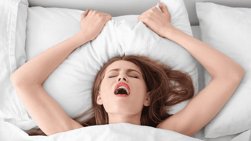 A woman in bed, either snoring really badly or having an orgasm.