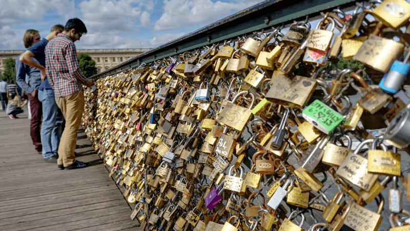 love lock bridge in paris with lots of padlocks attached to the fence